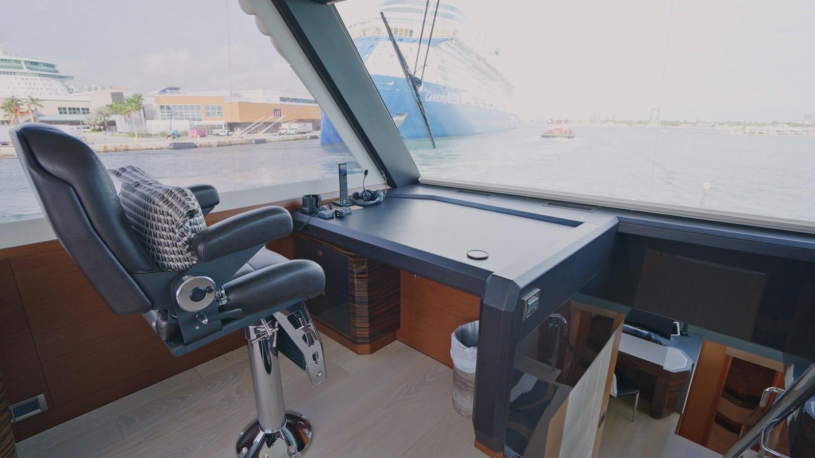 a black office chair next to a table with a large window aboard PANACEA Yacht for Sale