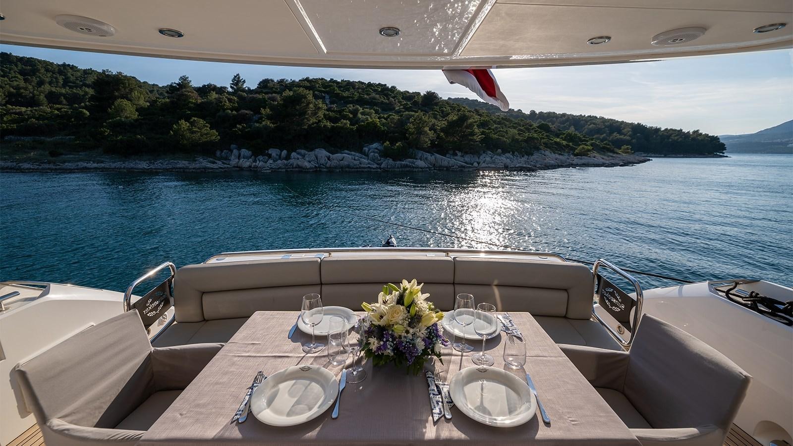 a table with plates and glasses on it by a body of water aboard CARDANO Yacht for Sale