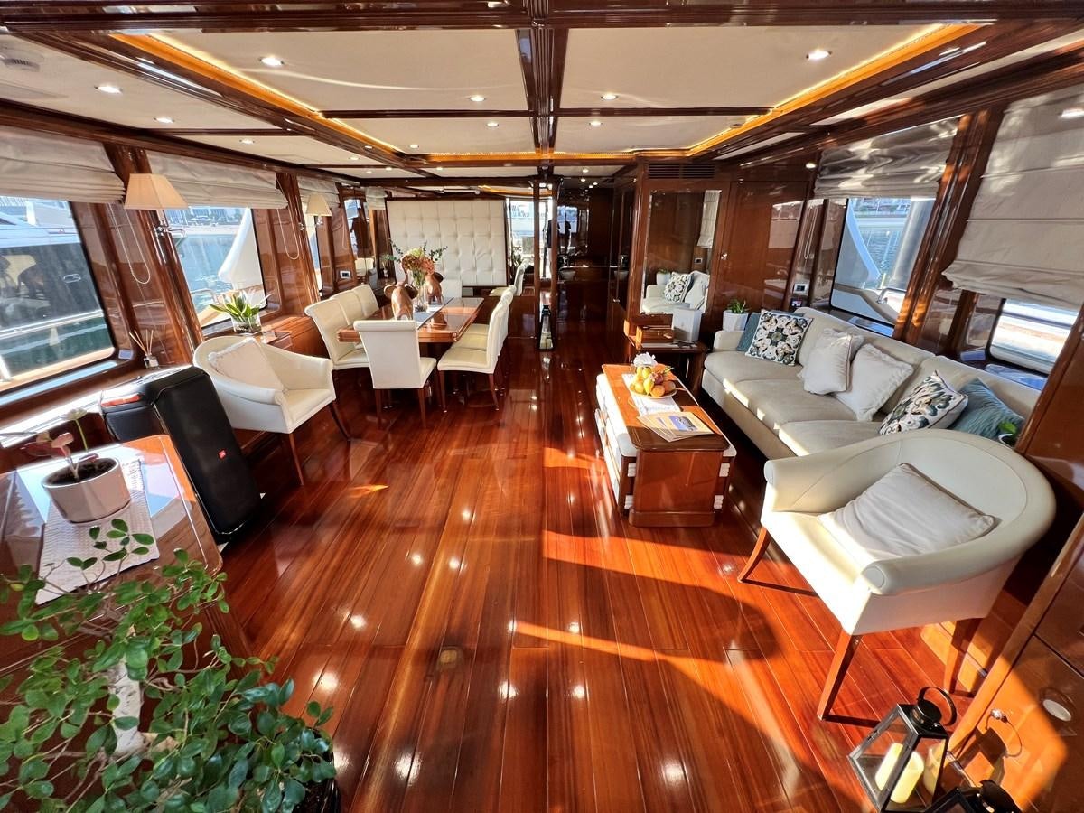 a room with a wood floor and a couch and a table with chairs aboard 2009 BENETTI 85 LEGEND Yacht for Sale