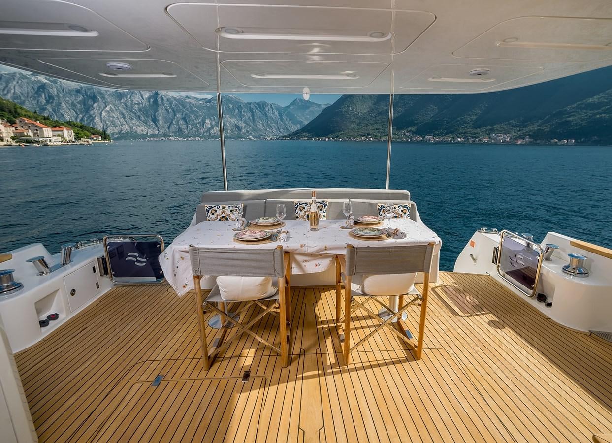 a table set for a meal on a deck overlooking a large body of water aboard AVVENTURA Yacht for Sale