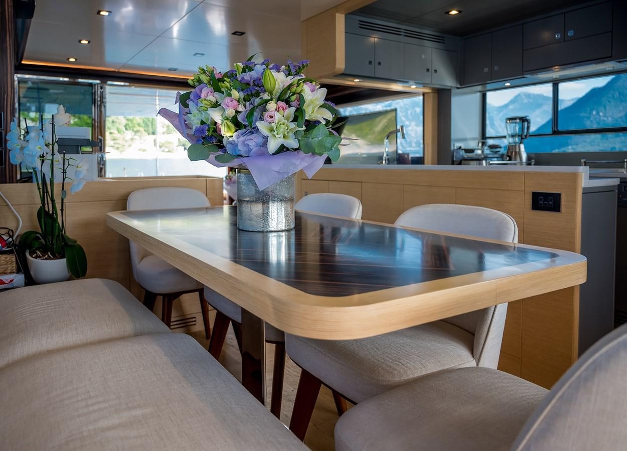 a table with chairs and a vase of flowers on it aboard AVVENTURA Yacht for Sale
