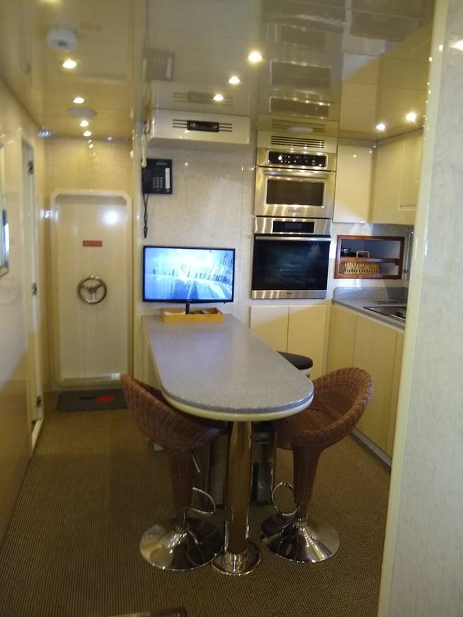 a table with chairs and a television aboard ALCHEMIST Yacht for Sale