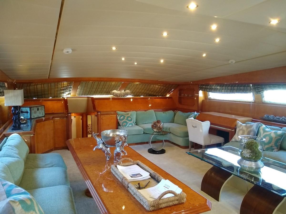 a living room with a large wood table and a large window aboard ALCHEMIST Yacht for Sale