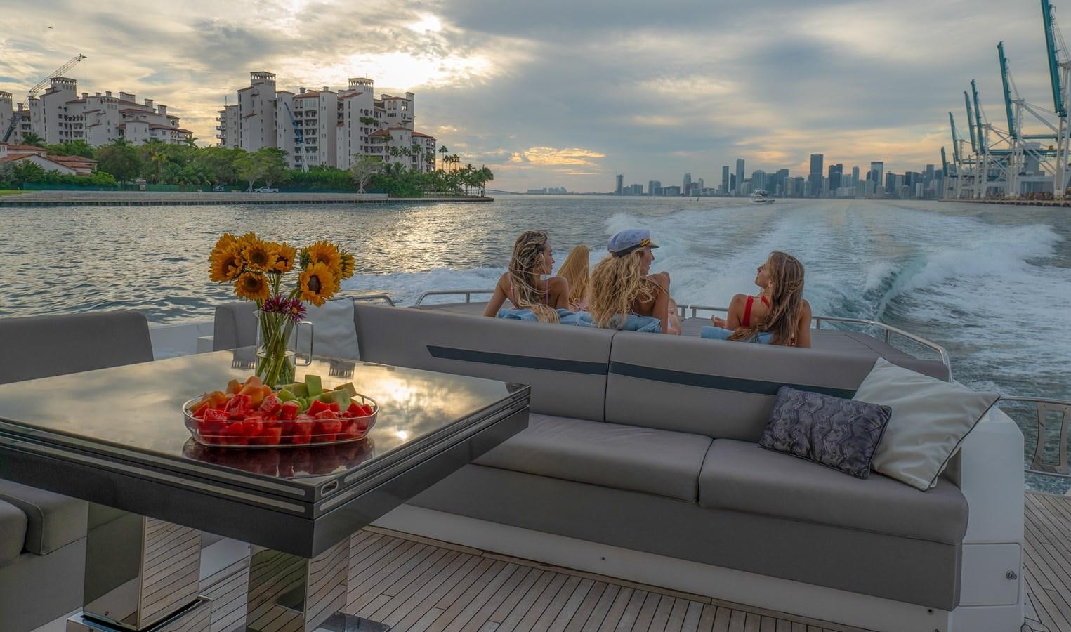 a group of people sitting on a couch on a boat with a city in the background aboard BELLOW DECK Yacht for Sale