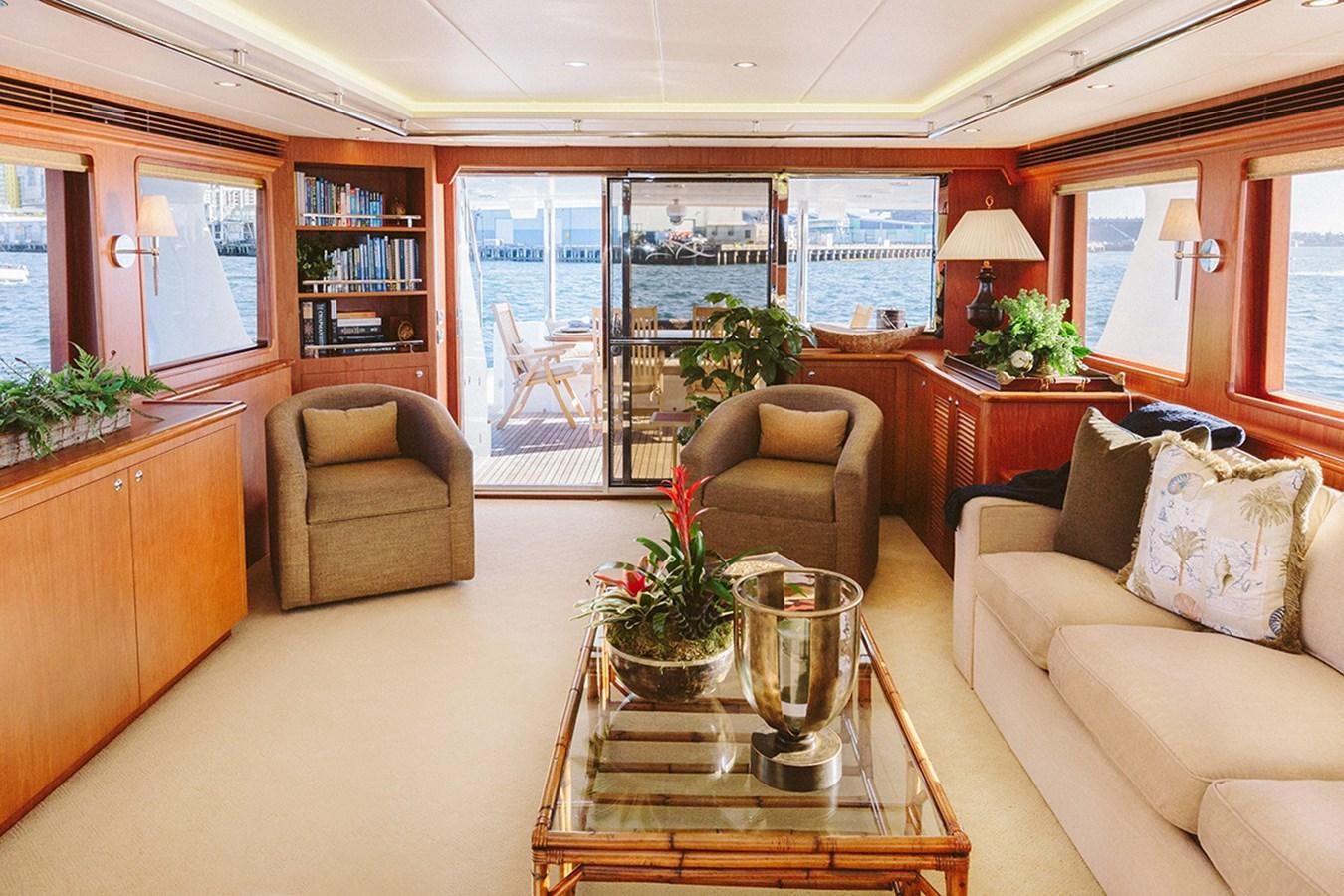 a living room with a glass coffee table and a view of the city aboard 44 NORTH Yacht for Sale