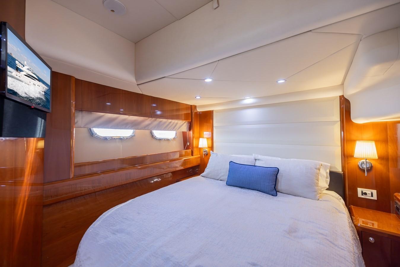 a bed with a wood headboard and a television on the wall aboard ODYSSEA Yacht for Sale