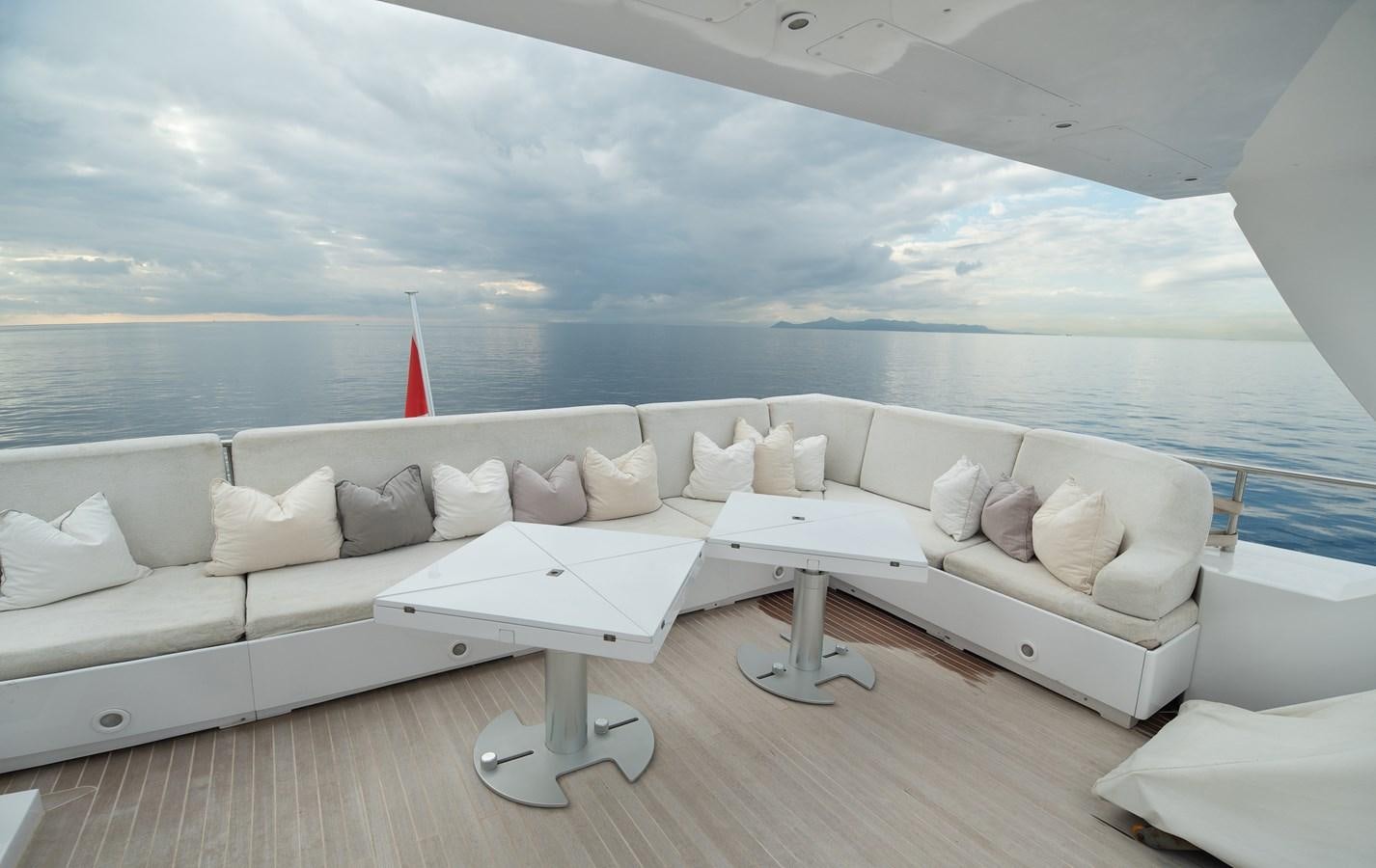 a white couch and a table in a room with a large body of water aboard XANAX Yacht for Sale
