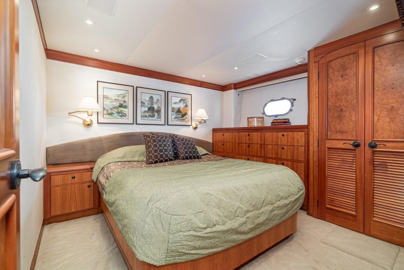a bedroom with a bed and a wood cabinet aboard BESAME Yacht for Sale