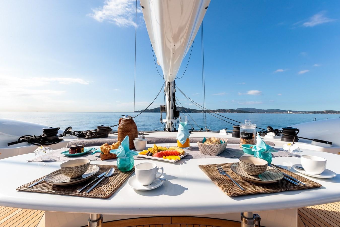a table with food and a large body of water in the background aboard ALLURES Yacht for Sale