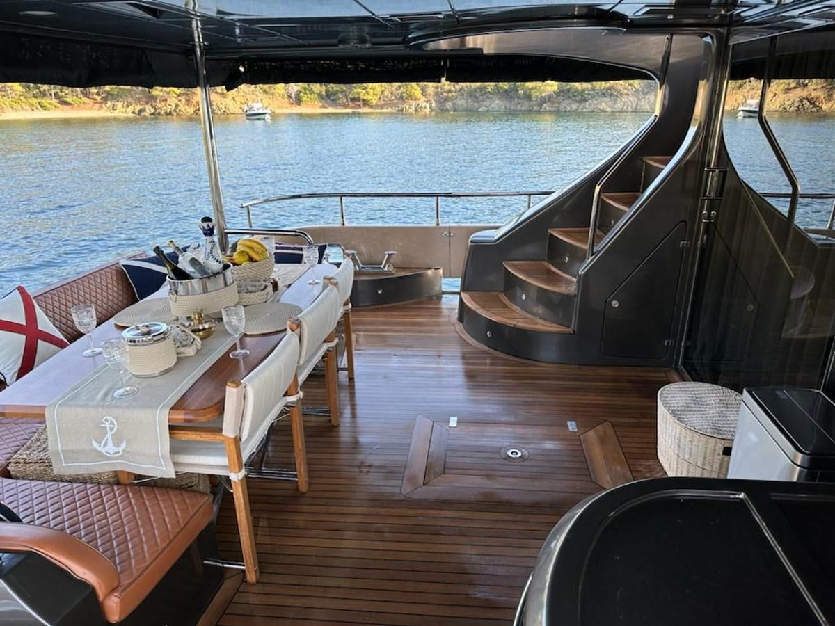 a deck with tables and chairs on it aboard AOP Yacht for Sale