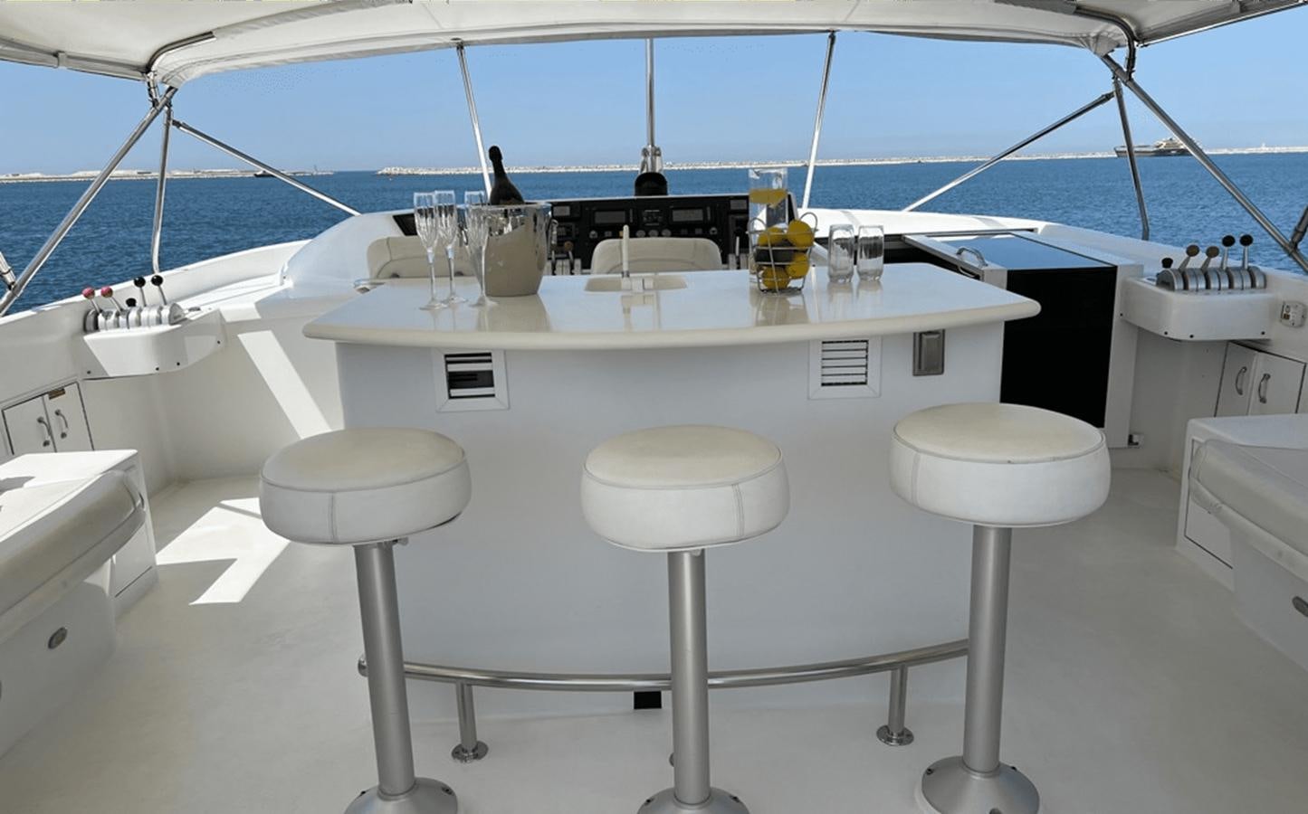 a white table with stools and stools aboard 1998 HATTERAS 92 Yacht for Sale