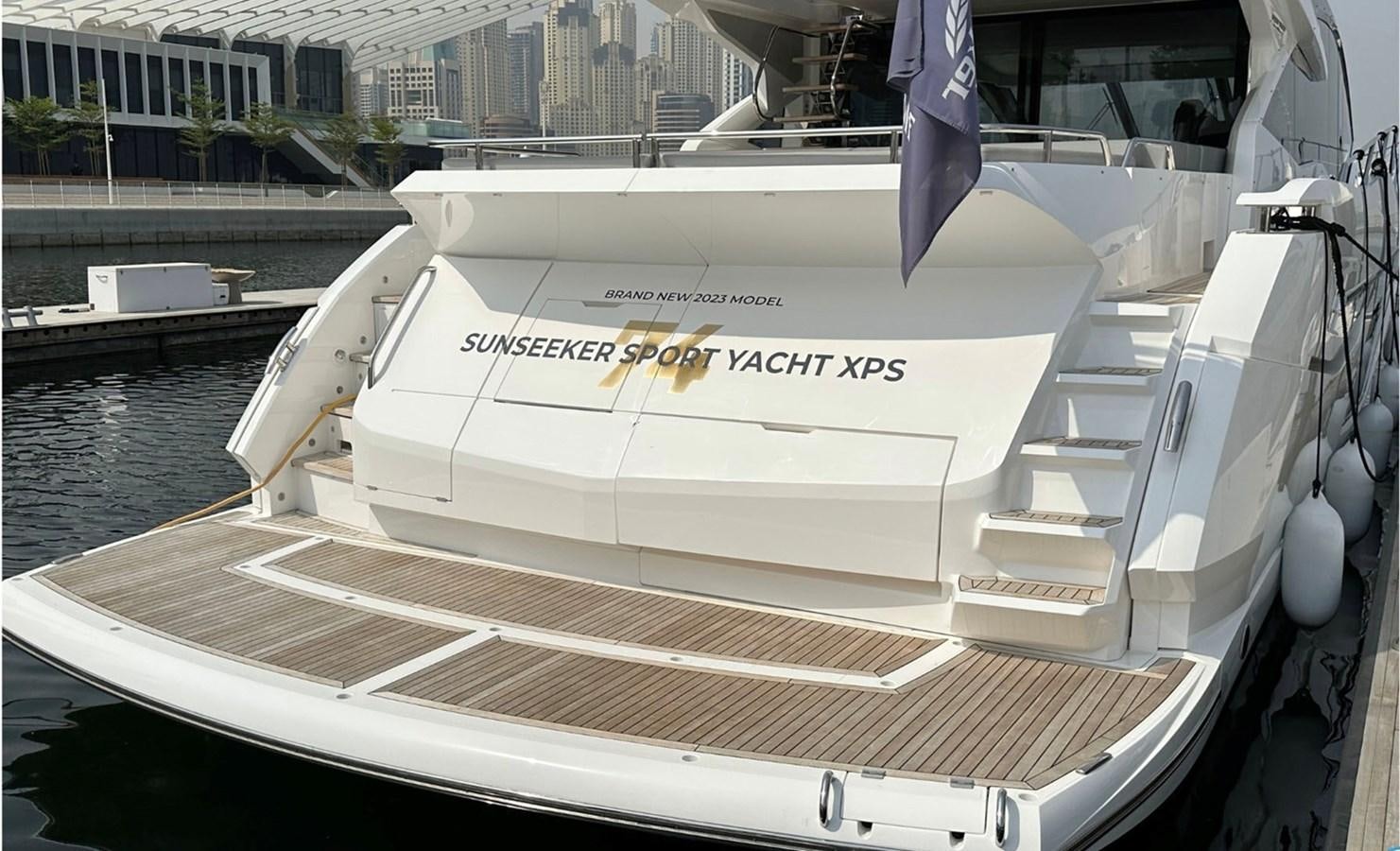 a white boat with a blue flag on it aboard 2023 SUNSEEKER 74 SPORTS  XPS Yacht for Sale