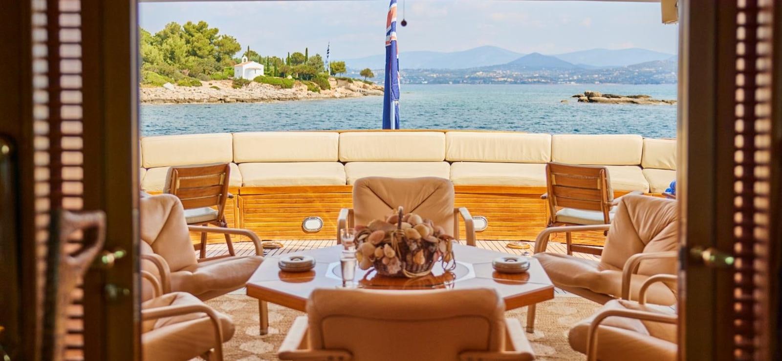 a table with chairs and a glass of water on a balcony aboard AETEA Yacht for Sale