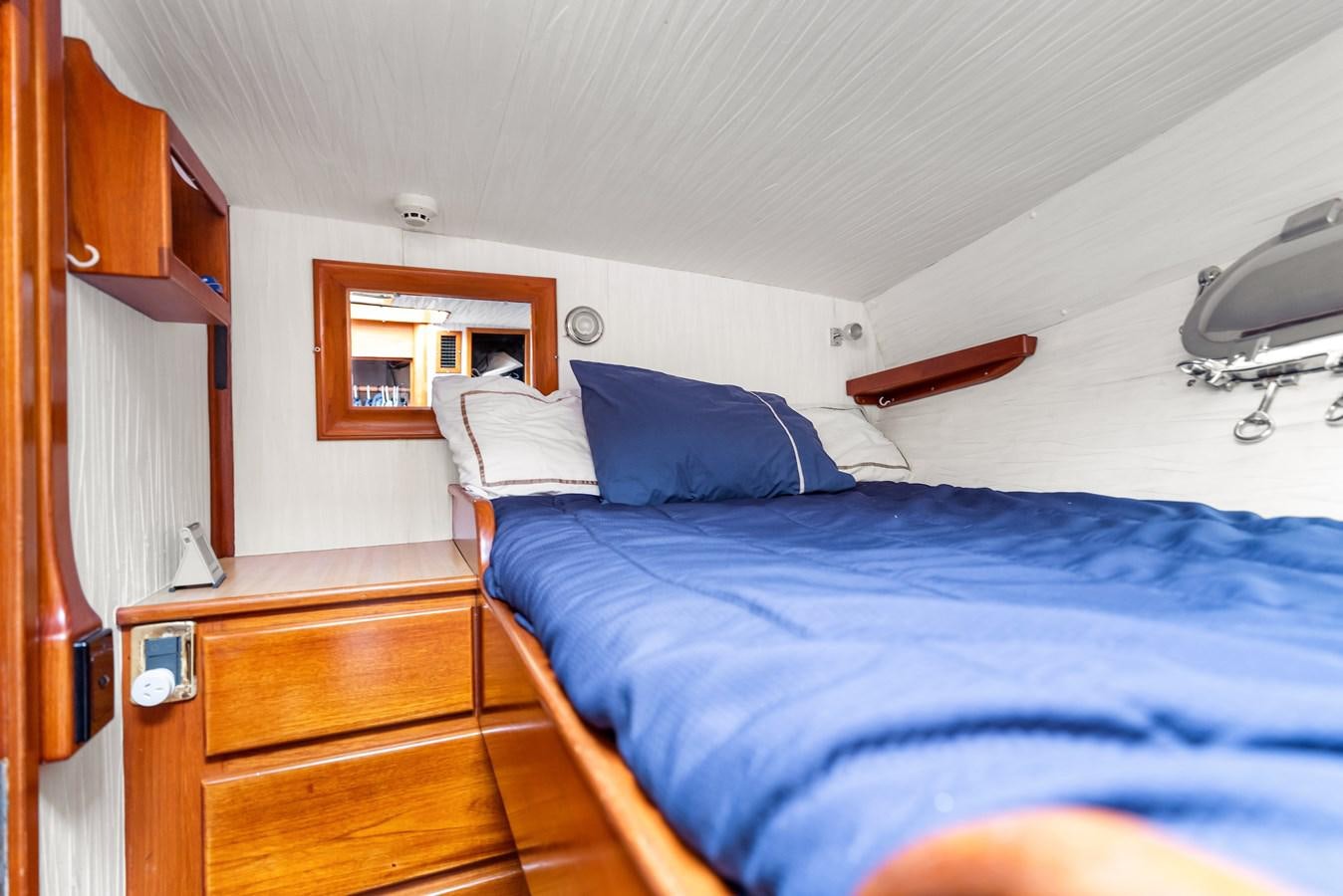 a bedroom with a bed and a dresser aboard HUNTRESS Yacht for Sale