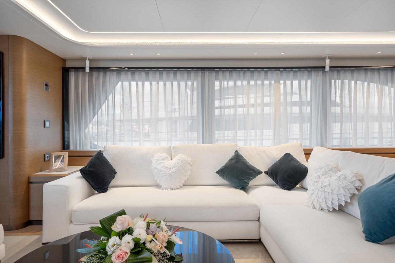 a white couch with pillows and a table in front of a window aboard JASMINE LUNA Yacht for Sale