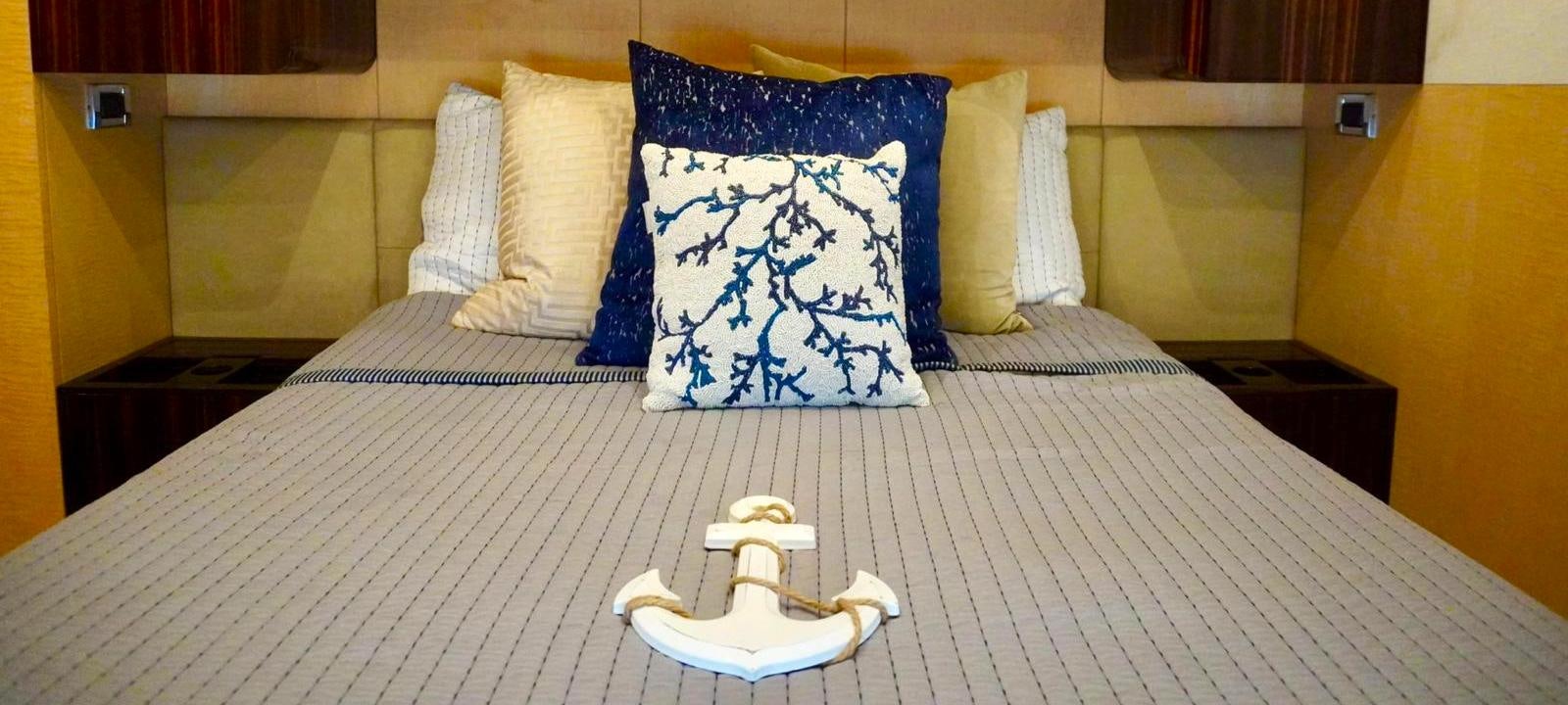 a bed with a blue and white pillow and a white toy robot on it aboard OUR TIME Yacht for Sale