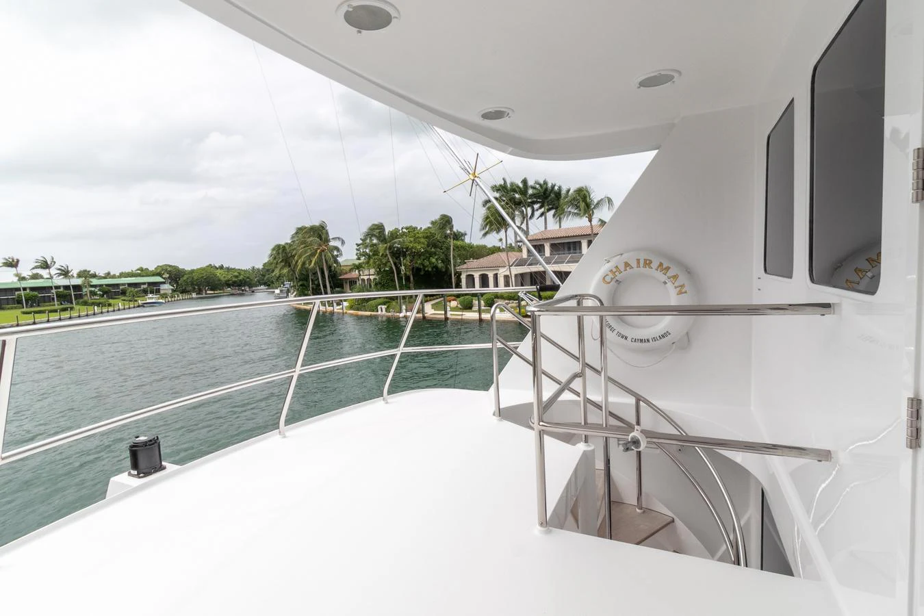a white boat with a white railing and a pool with a pool and trees and a building in aboard CHAIRMAN Yacht for Sale