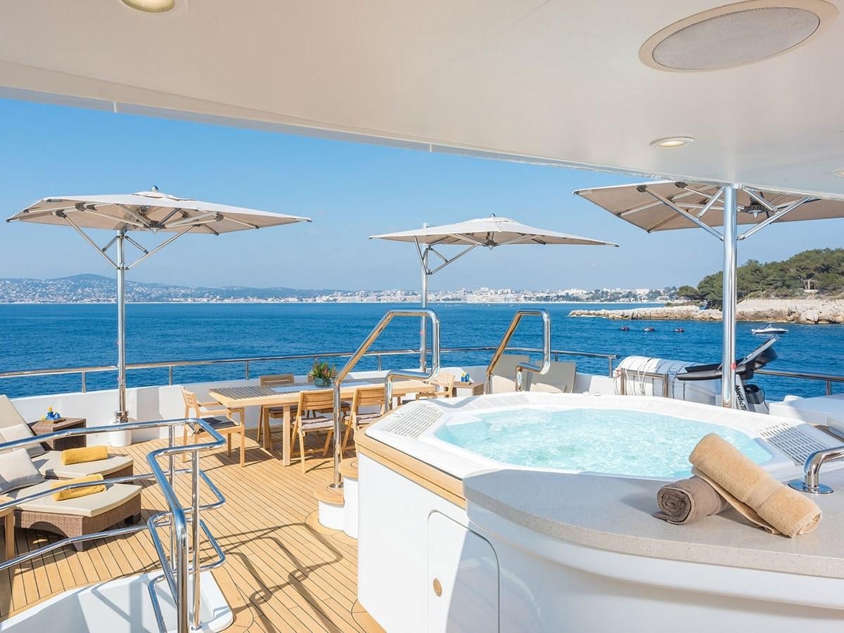 a pool with umbrellas and chairs on a deck by the ocean aboard JADE 959 Yacht for Sale