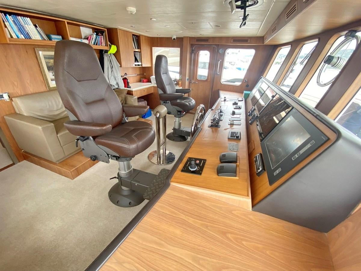 a room with a tv and chairs aboard O Yacht for Sale