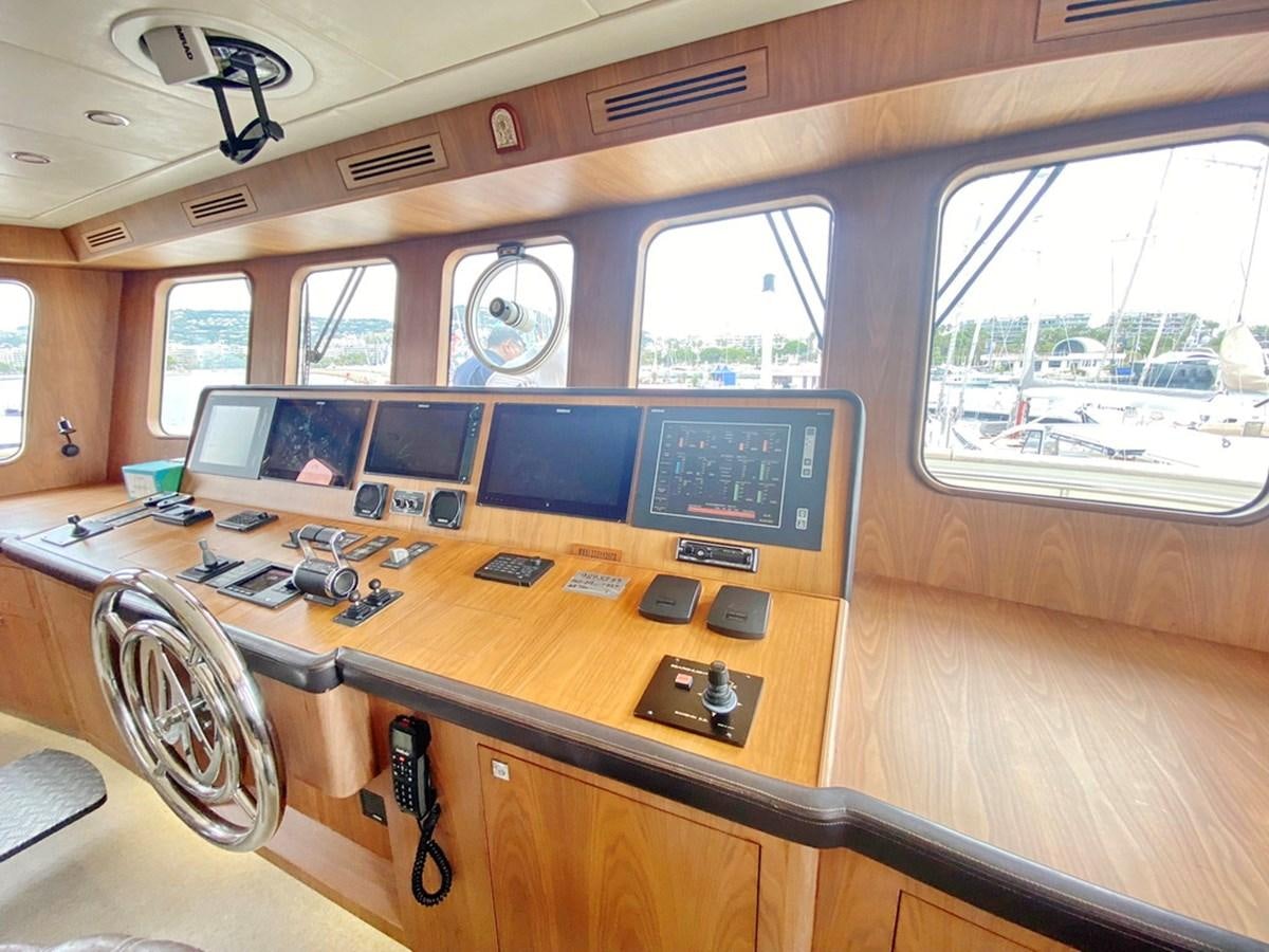 a wooden desk with a computer and other electronics on it aboard O Yacht for Sale