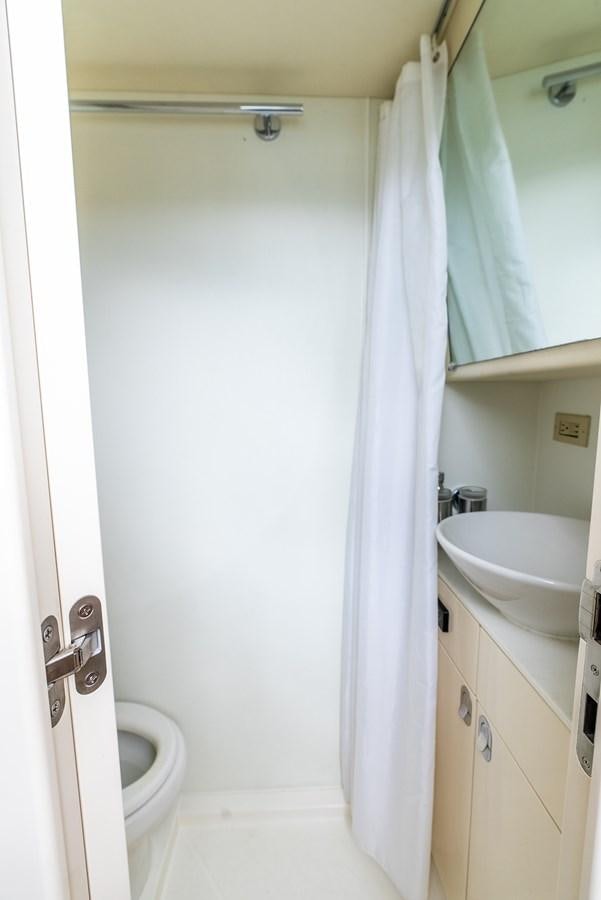 a small bathroom with a white curtain aboard SHANTI Yacht for Sale