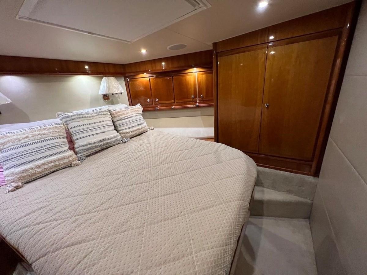 a bedroom with a bed and a wood cabinet aboard BEACH BUM Yacht for Sale