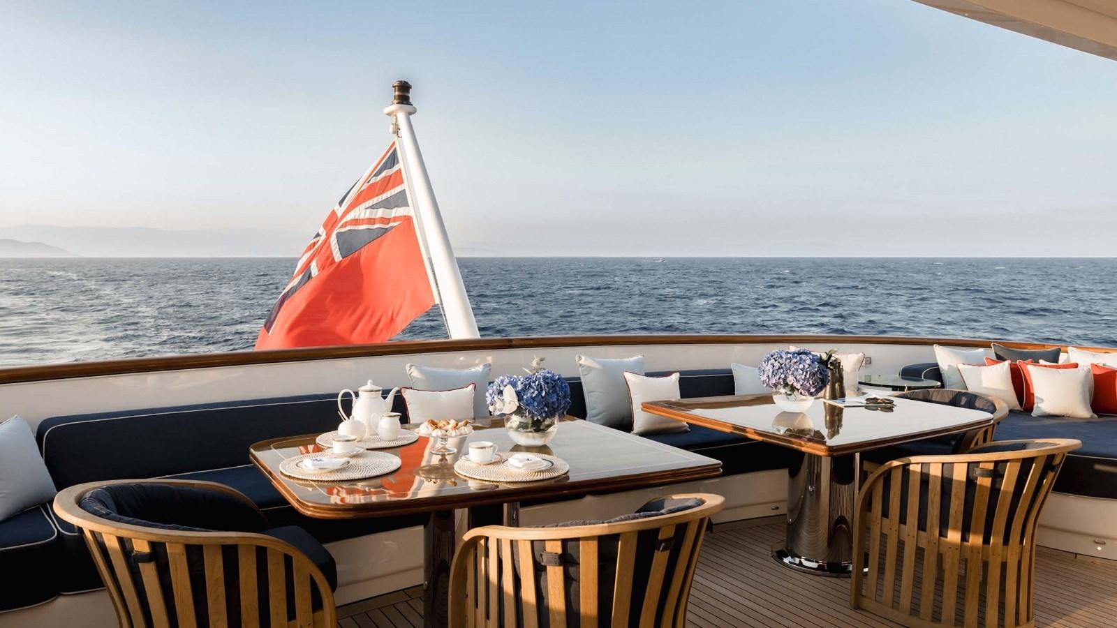 a table with chairs and a sailboat on it aboard OLYMPUS Yacht for Sale