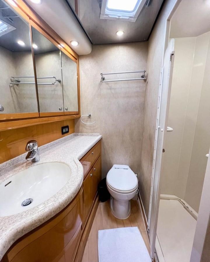a bathroom with a toilet sink and a mirror aboard BERTRAM 66 Yacht for Sale