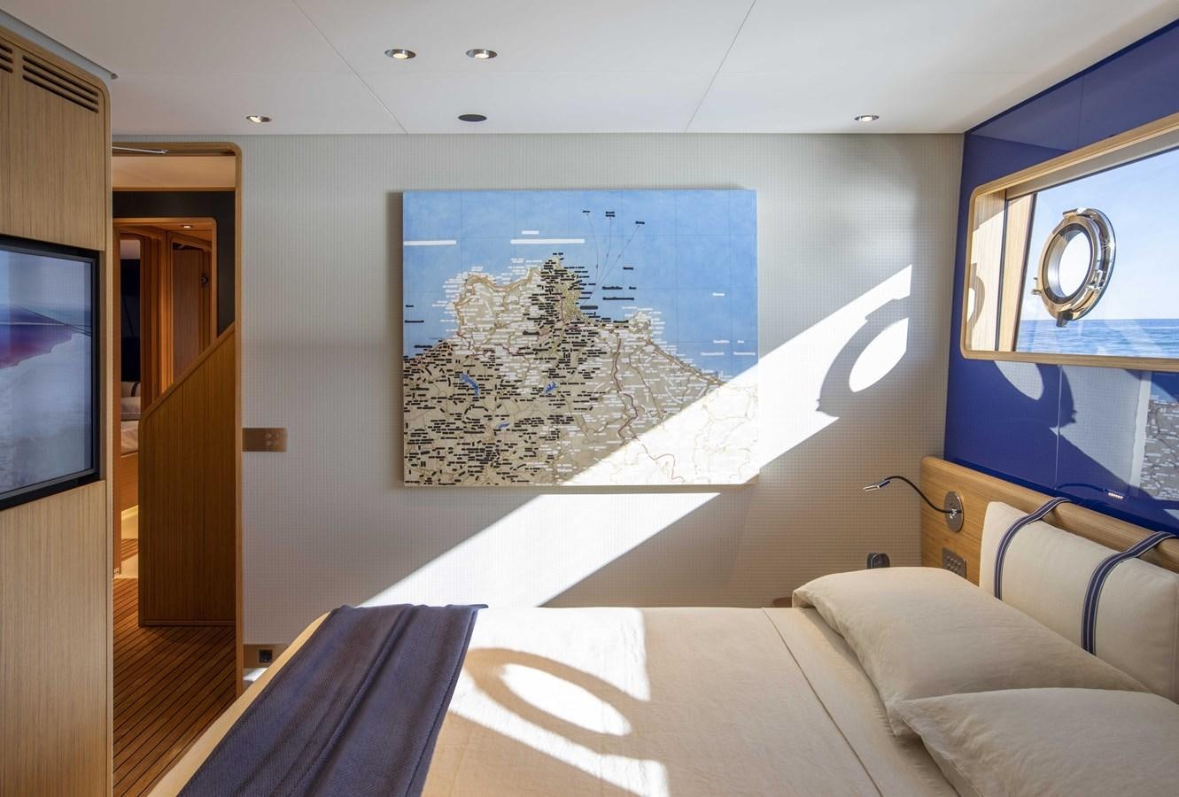 a bed with a blue wall and a painting on the wall aboard CUSTOM LINE NAVETTA 33/33 Yacht for Sale