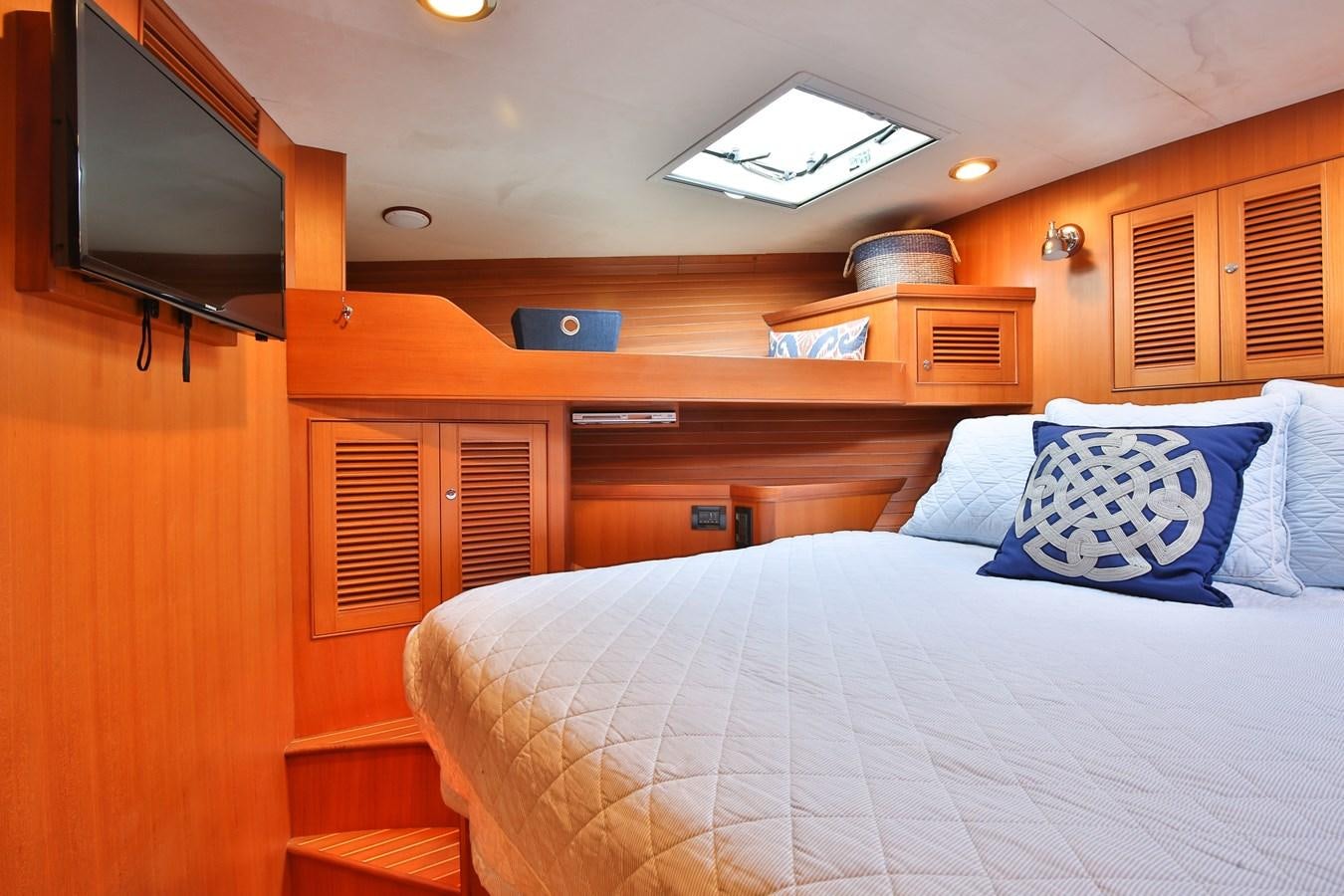 a bed with a white sheet and a television on the wall aboard BESPOKE Yacht for Sale