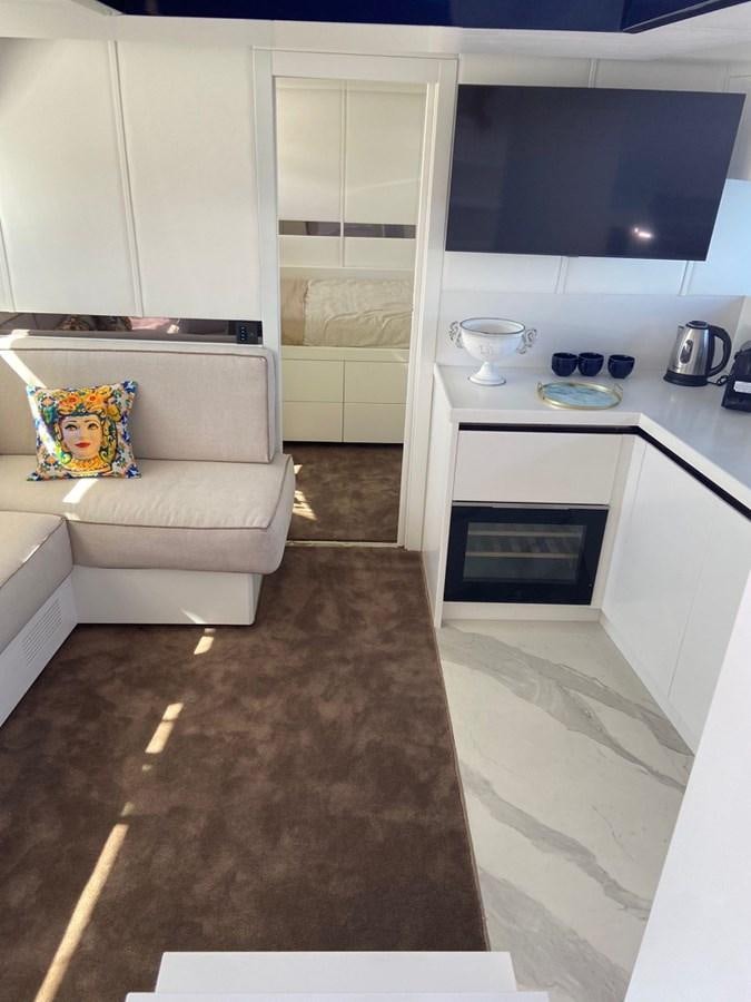 a small living room with a white couch and a white cupboard aboard SUERT 70 Yacht for Sale