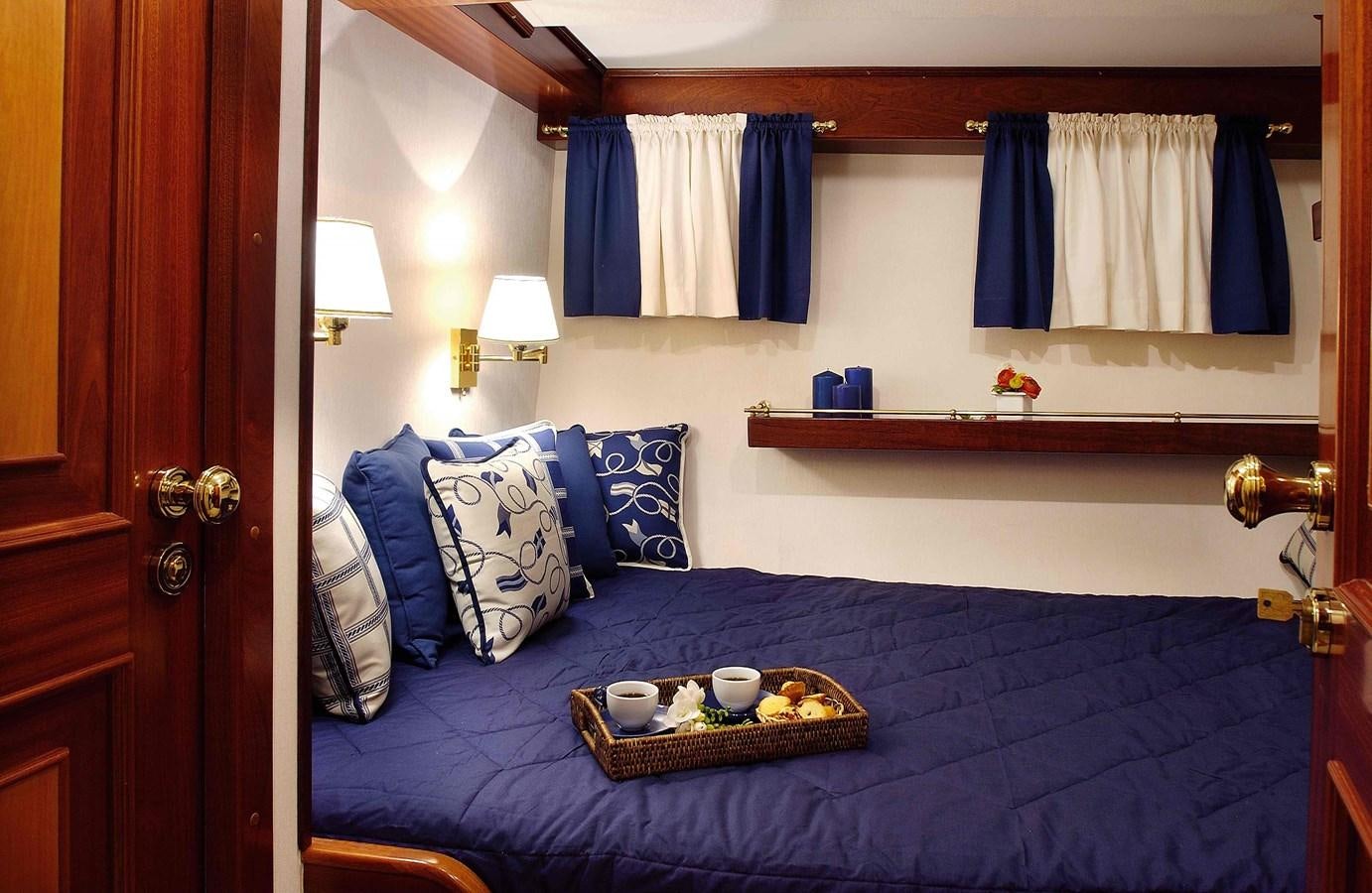 a bed with blue sheets and pillows aboard LIANA H Yacht for Sale