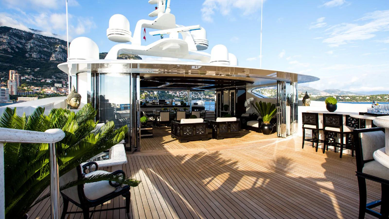 a deck with a large white building and a large white dome with a table and chairs and plants aboard LIONESS V Yacht for Sale