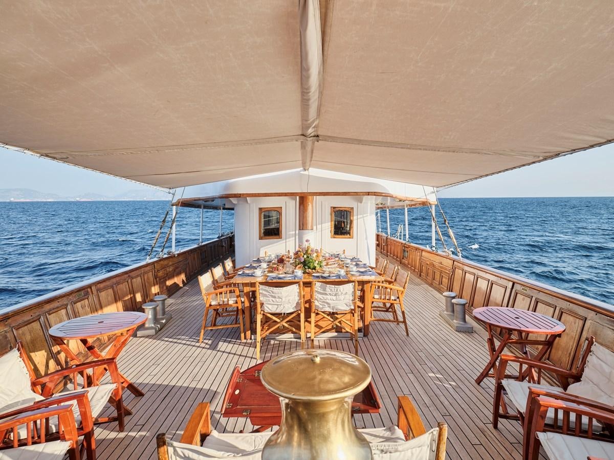 a restaurant with tables and chairs on a deck overlooking the ocean aboard MADIZ Yacht for Sale