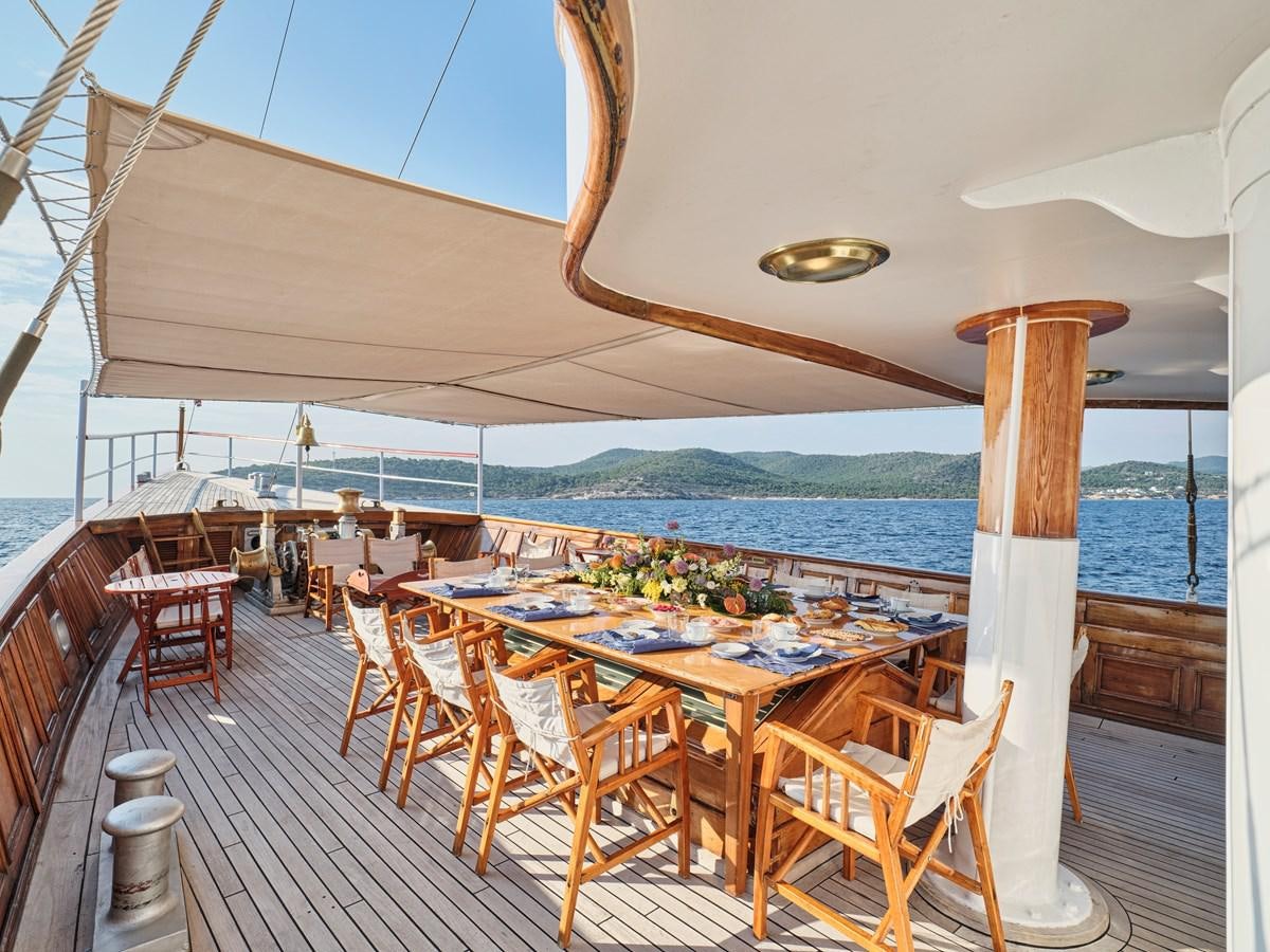 a deck with a table and chairs on it aboard MADIZ Yacht for Sale
