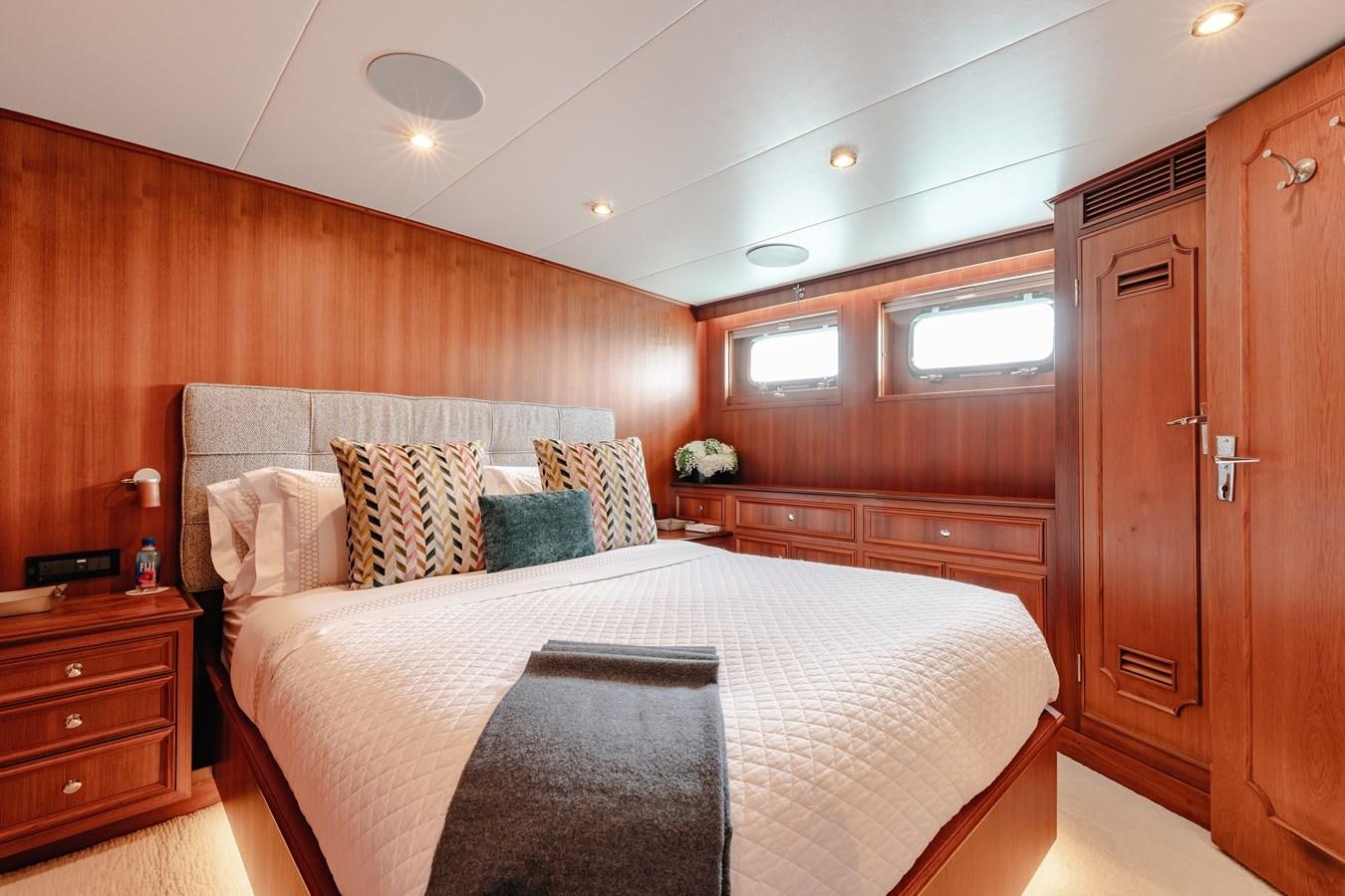 a bedroom with a bed and a wood cabinet aboard CALYPSO Yacht for Sale