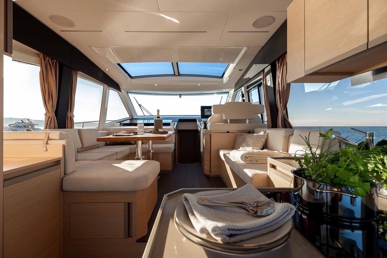 a room with a couch and a table with chairs and a large window aboard OCEAN CLASS 68 Yacht for Sale