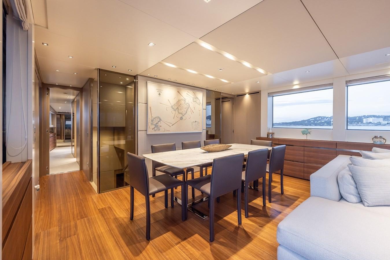 a dining table and chairs in a room with a large window aboard COBANA Yacht for Sale