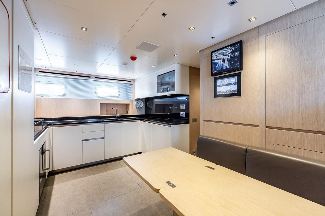 a kitchen with a table and a tv on the wall aboard COBANA Yacht for Sale