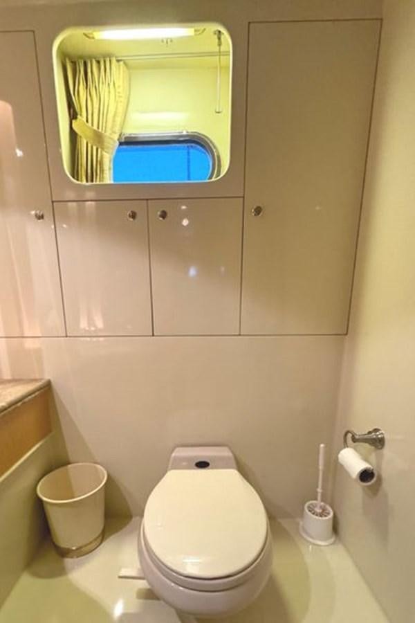 a bathroom with a toilet and a mirror aboard CLASSIFIED Yacht for Sale