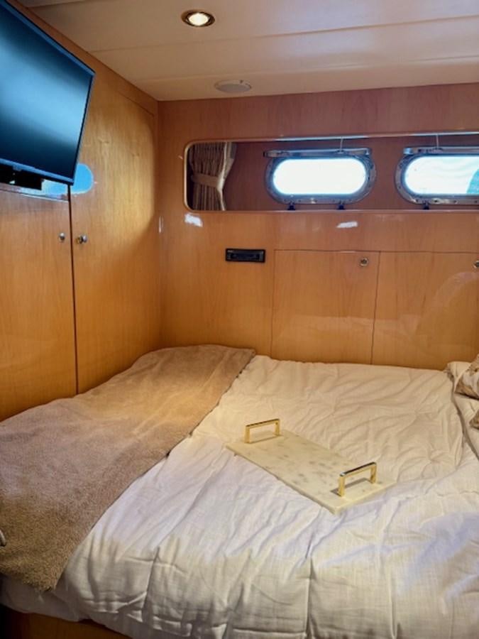 a bed with a television on the wall aboard CLASSIFIED Yacht for Sale