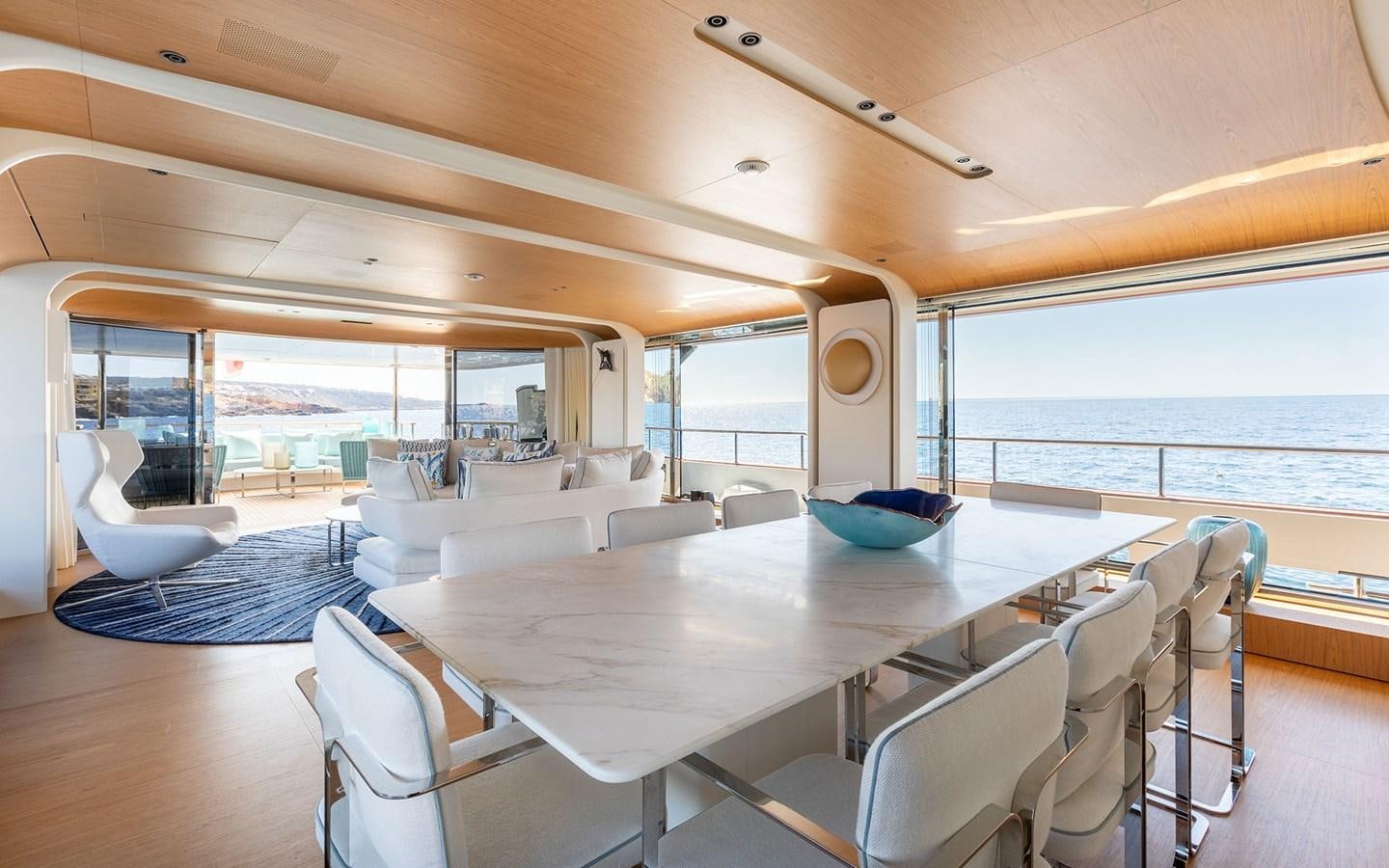 a large white dining table in a room with a large window aboard EH2 Yacht for Sale