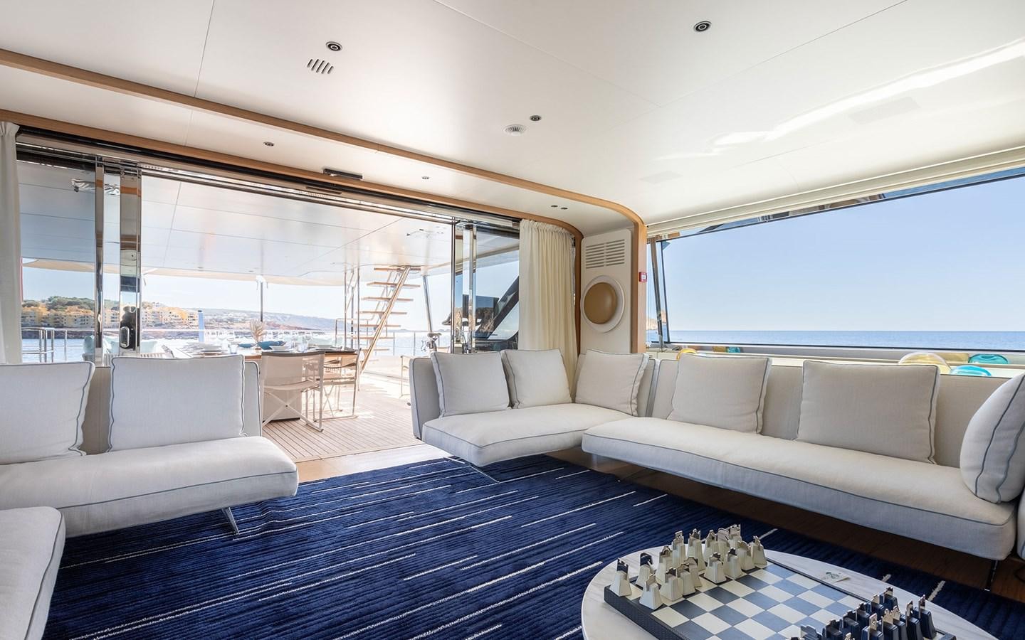 a living room with a large blue rug and white couches aboard EH2 Yacht for Sale