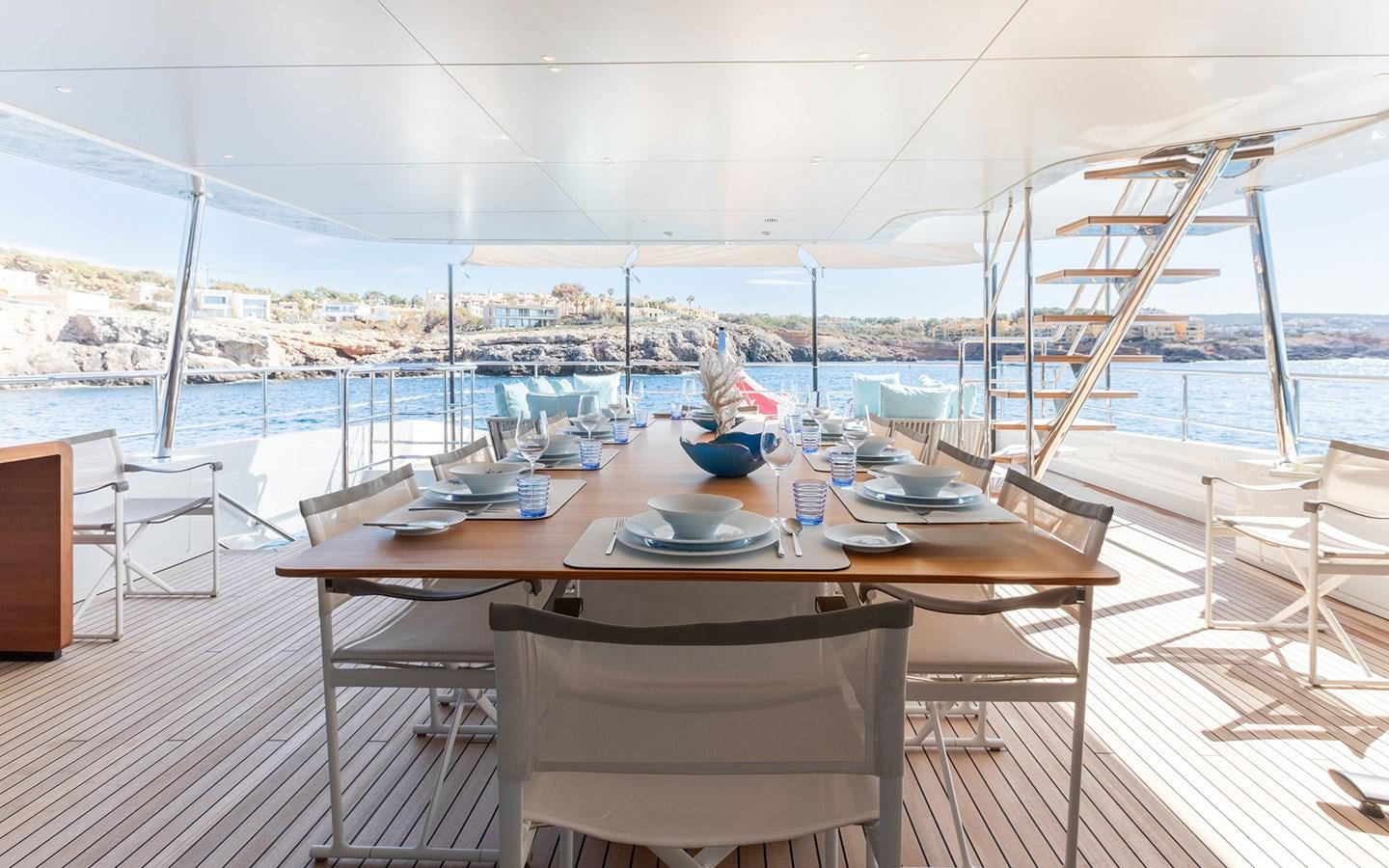 a table set for a meal on a deck overlooking a large body of water aboard EH2 Yacht for Sale