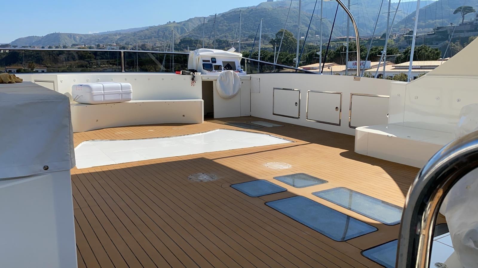 a deck with a deck and a view of mountains aboard MR GU Yacht for Sale