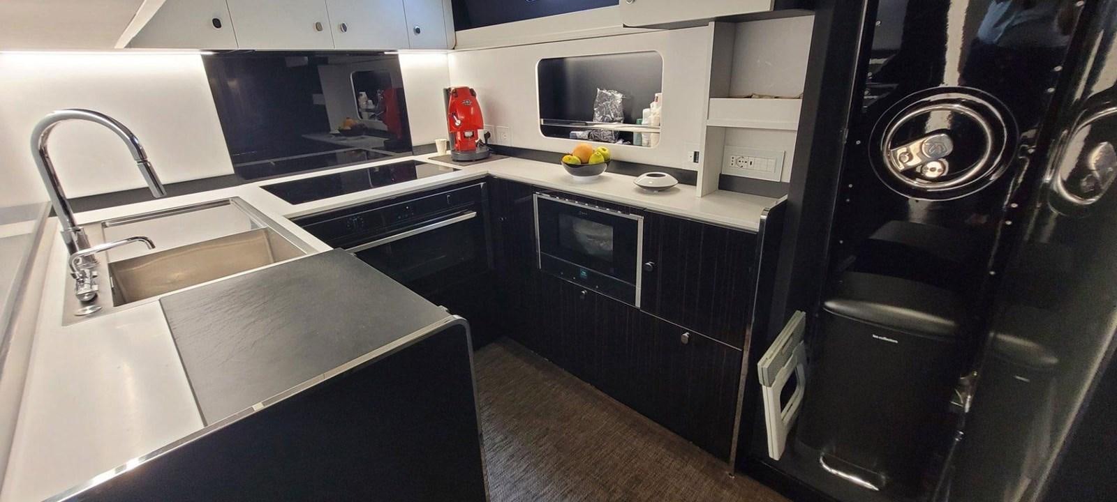 a kitchen with black cabinets aboard POSILLIPO TECHNEMA 90 Yacht for Sale