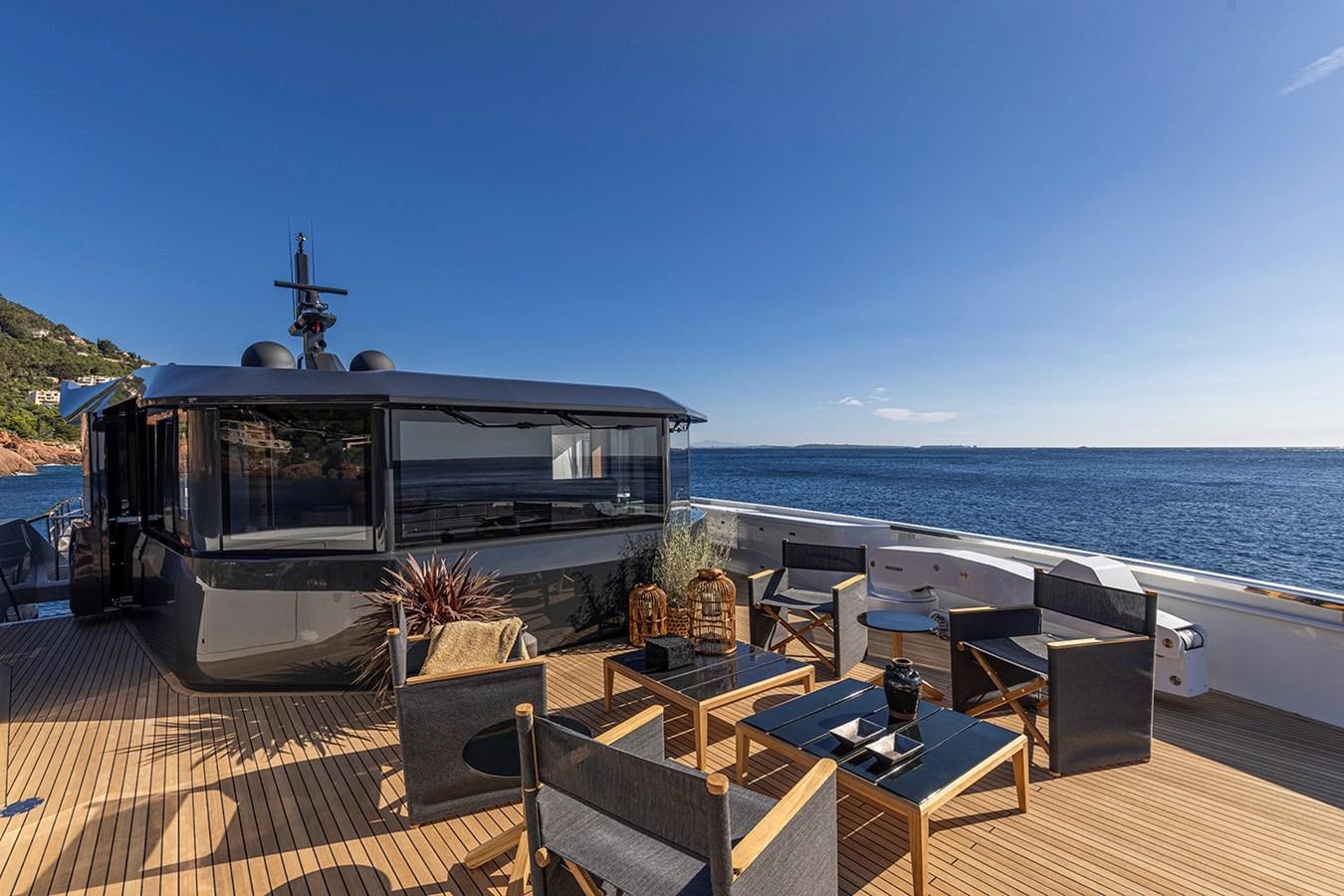 a deck with a table and chairs on it by the water aboard ARCADIA 96 Yacht for Sale