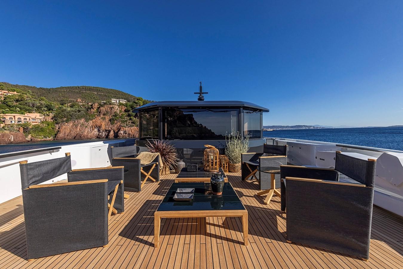 a patio with a table and chairs on it by the water aboard ARCADIA 96 Yacht for Sale