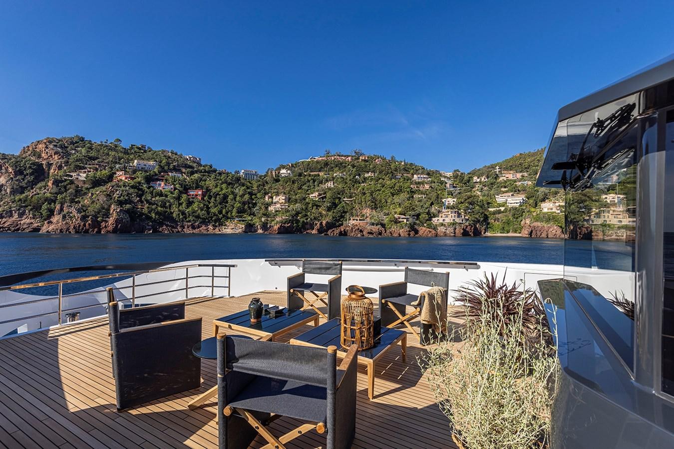 a deck with chairs and a body of water and trees in the background aboard ARCADIA 96 Yacht for Sale