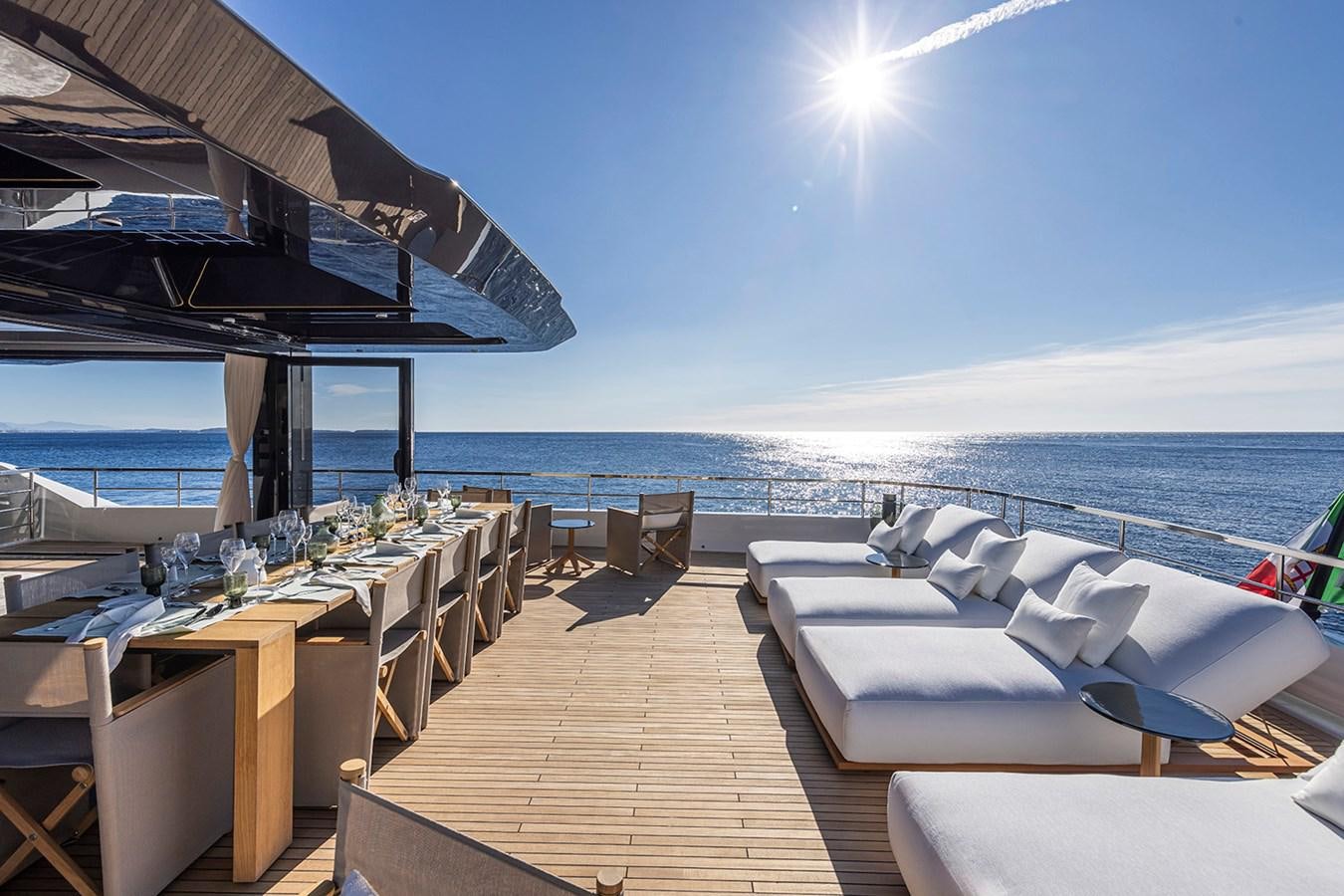 a deck with tables and chairs on it next to a body of water aboard ARCADIA 96 Yacht for Sale